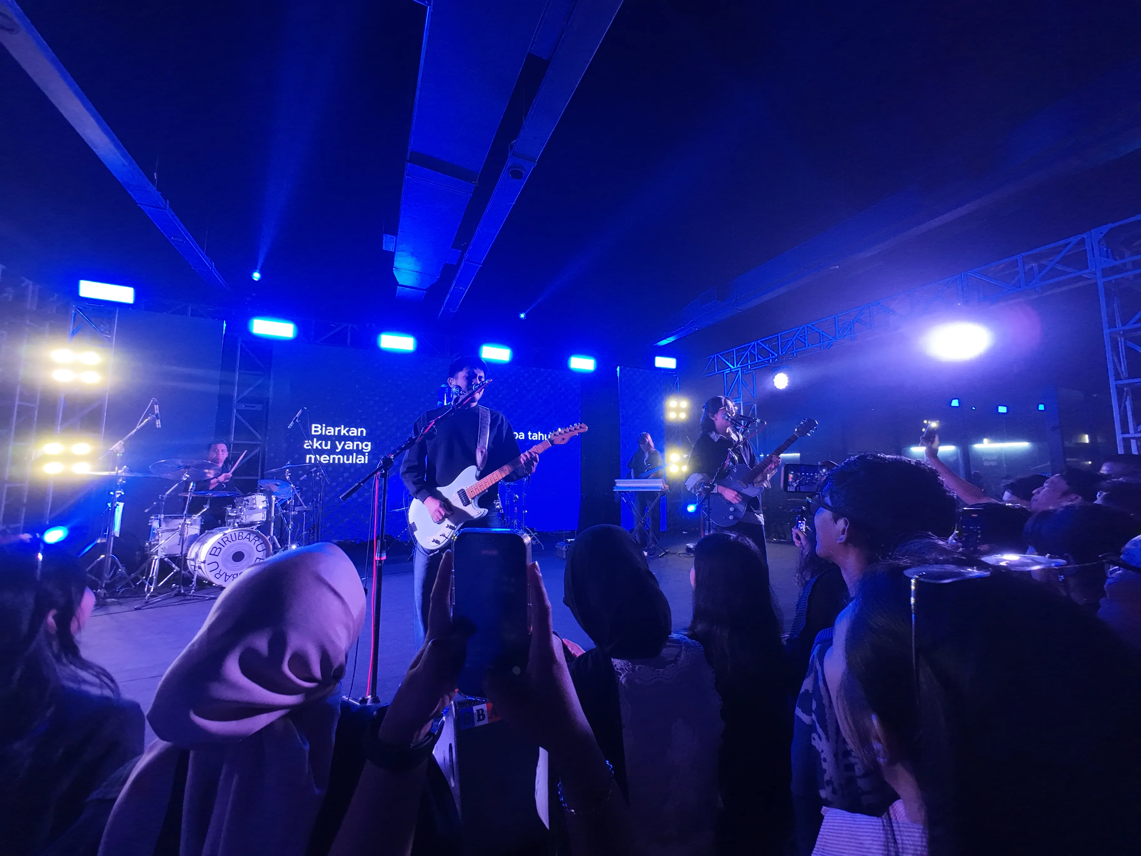 Band tampil di panggung berlampu biru